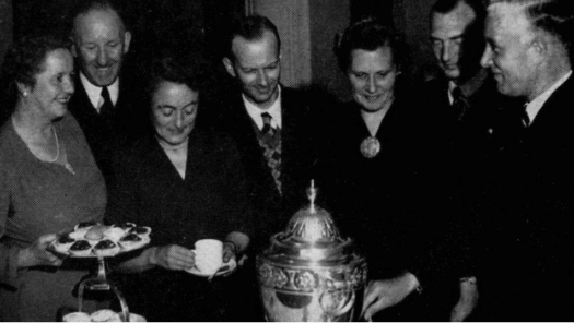 Black and white image of men and women enjoying tea and pastries
