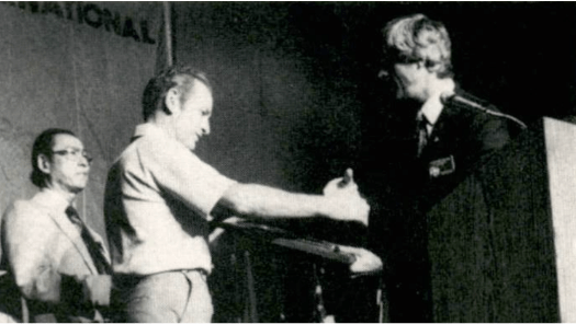 Black and white photo of a man accepting an award from another man