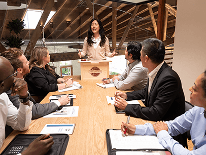 Woman standing at lectern speaking to people at table