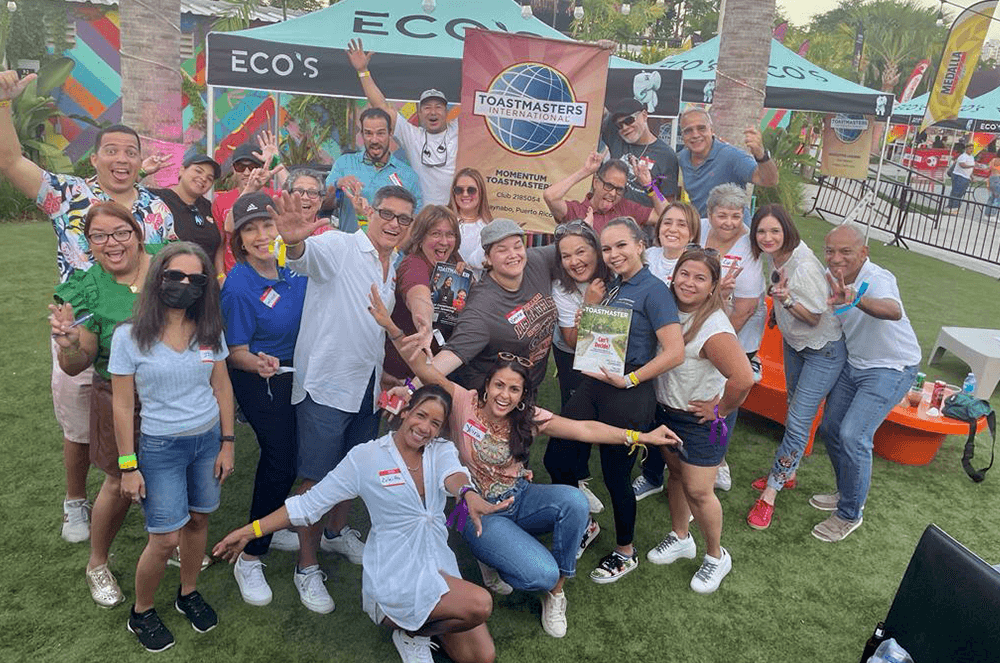 Group of people posing outdoors with club banner