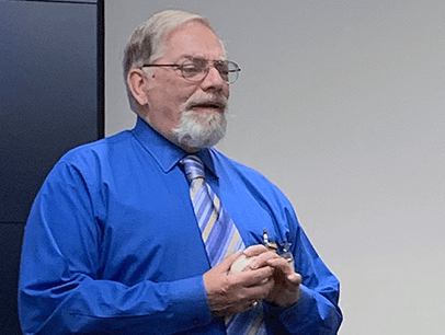Man in blue shirt and tie speaking