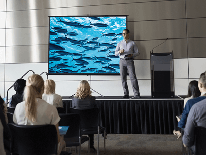 Man onstage giving presentation