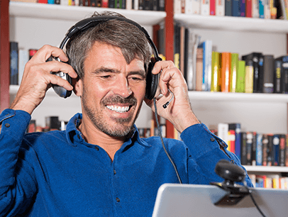 Man in blue shirt adjusting headphones while videoconferencing