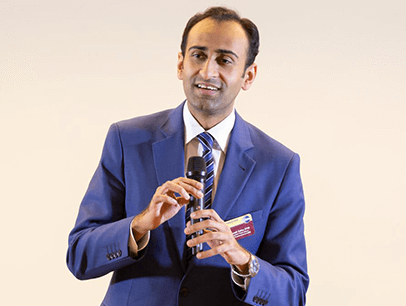 Man wearing blue suit and talking in microphone
